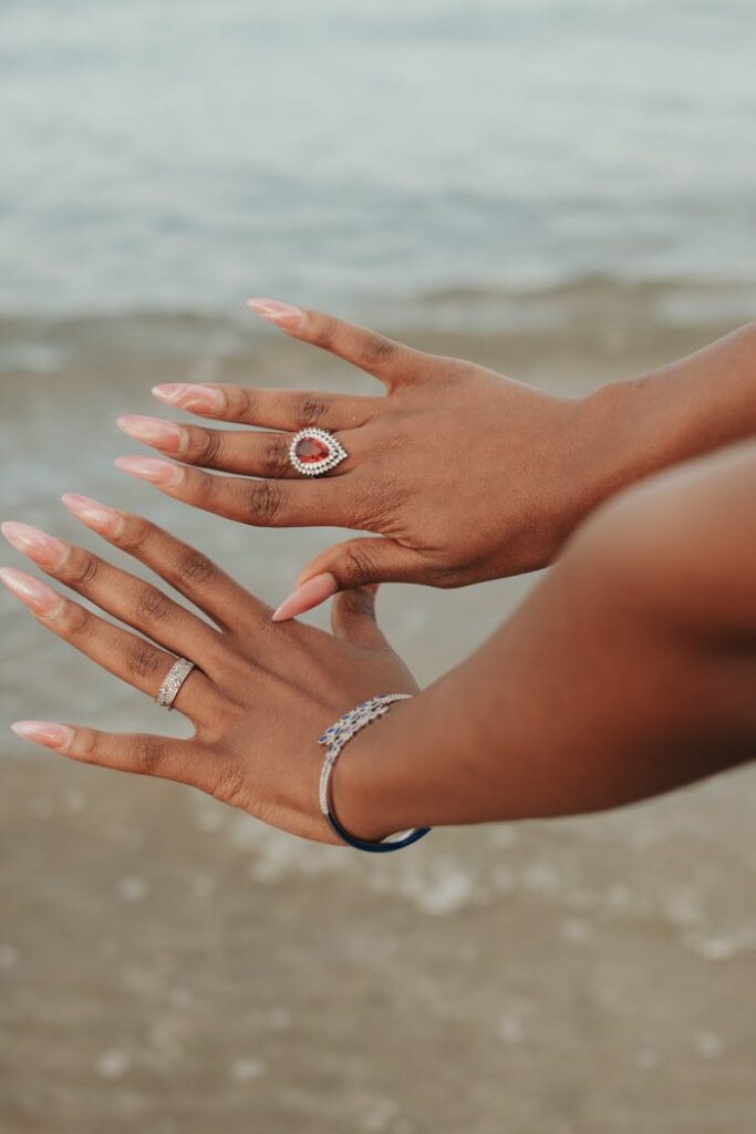 Close-up of accessorized hands with rings and bracelets at Yeni İskele beach.