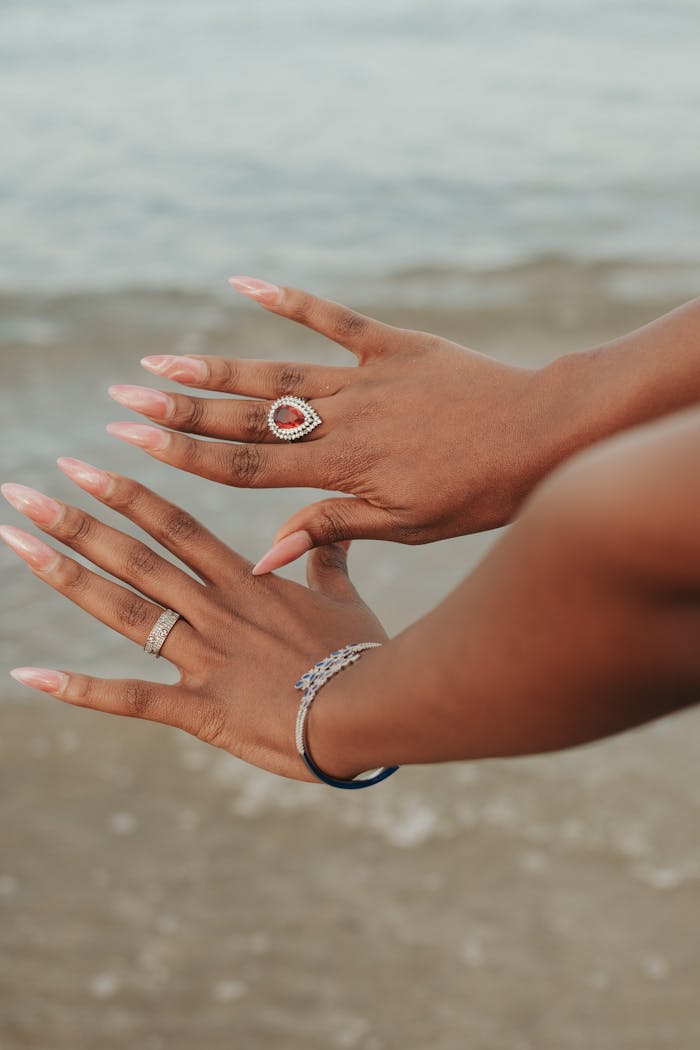 Close-up of accessorized hands with rings and bracelets at Yeni İskele beach.