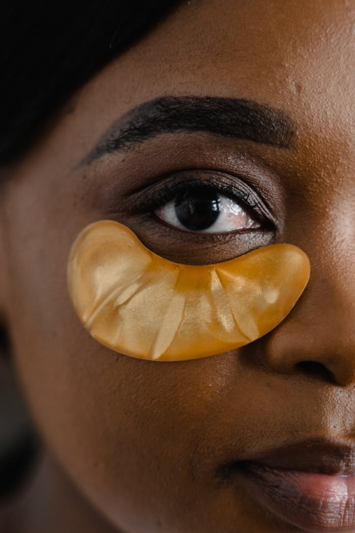 Detailed close-up of a woman's eye with a gold cosmetic eye patch for skincare.
