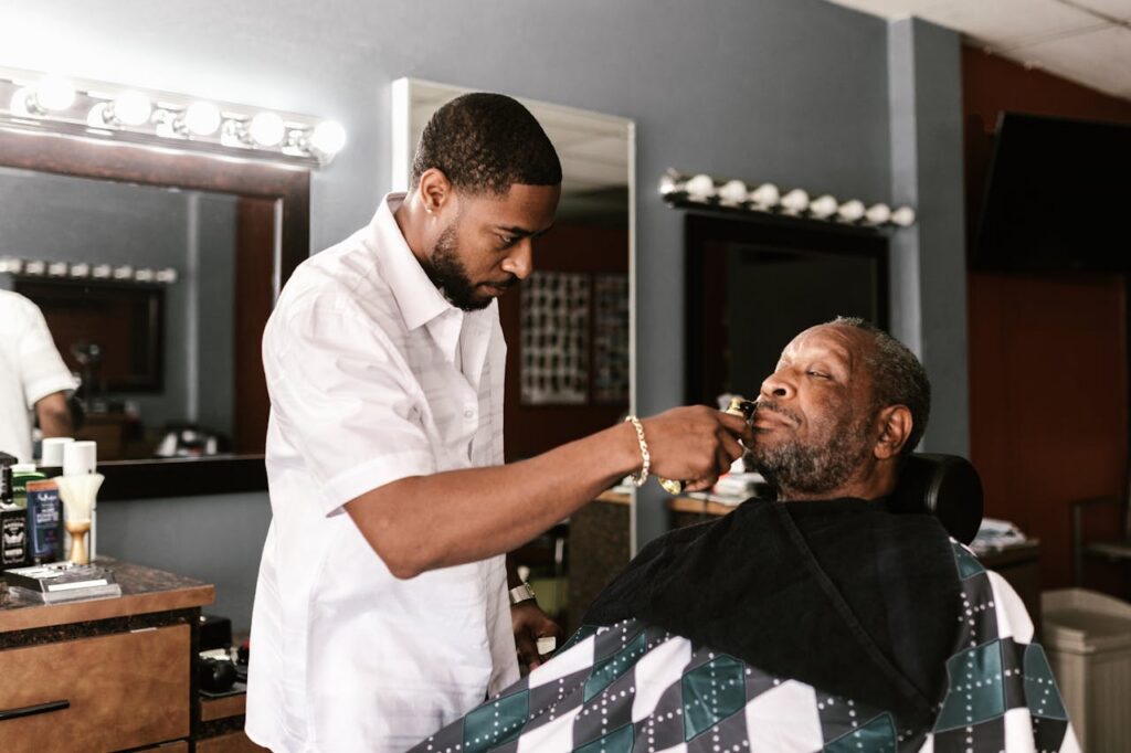 A barber professionally trims a client's beard in a stylish barbershop setting.